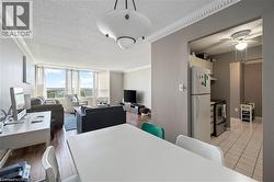 Open-concept living area with wood-finish flooring, crown molding, and expansive windows - 