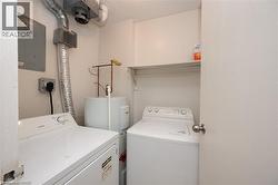 Dedicated laundry area featuring a washer and dryer, water heater, and wall-mounted shelving - 