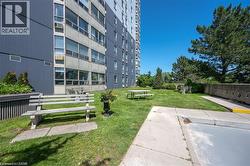 Expansive green space featuring a picnic table, multiple benches, and mature trees - 