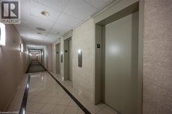 Elevator access with brushed metal controls, textured wall finishes, recessed ceiling lighting, and polished tile flooring with a dark accent border - 