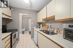 Kitchen featuring a dual basin sink, white cabinetry, a built-in range, a built-in dishwasher, and tiled flooring - 
