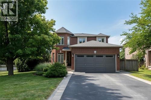 Brick exterior with a prominent two-car garage, asphalt driveway, and mature landscaping.  Parking for 4 vehicles on driveway and 2 inside garage - 470 Amanda Crescent, Burlington, ON - Outdoor With Facade