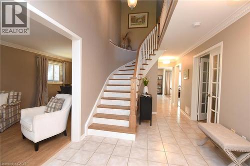 Curved staircase with wood treads and white risers, tile flooring, crown molding, and French doors - 470 Amanda Crescent, Burlington, ON - Indoor Photo Showing Other Room