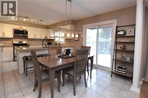 Kitchen featuring light-toned cabinetry, stainless steel appliances, a tiled backsplash, and a central island with a breakfast bar - 470 Amanda Crescent, Burlington, ON - Indoor Photo Showing Other Room