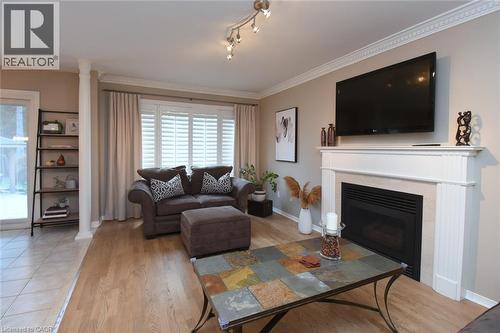 Fireplace with a classic white mantel, wood-finish flooring, white window shutters, and track lighting - 470 Amanda Crescent, Burlington, ON - Indoor Photo Showing Living Room With Fireplace