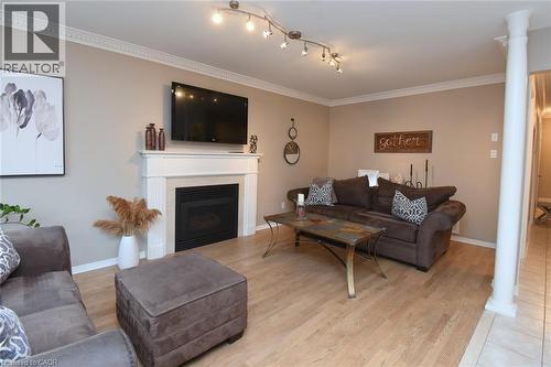 Living area featuring wood-finish flooring, crown molding, a fireplace with a white mantel, and track lighting - 470 Amanda Crescent, Burlington, ON - Indoor Photo Showing Living Room With Fireplace