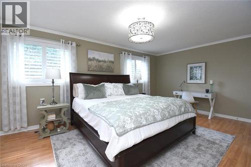 Recessed lighting, crown molding, wood-finish flooring, two windows with blinds, and a decorative ceiling fixture - 470 Amanda Crescent, Burlington, ON - Indoor Photo Showing Bedroom