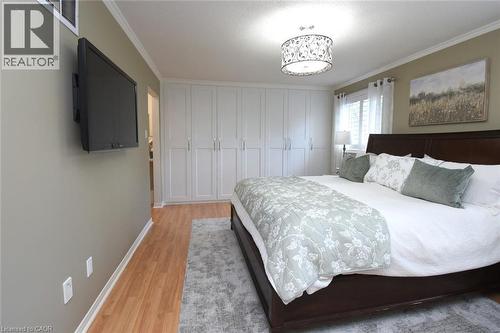 Wood-finish flooring, white built-in cabinetry, crown molding, and a drum-style ceiling light fixture - 470 Amanda Crescent, Burlington, ON - Indoor Photo Showing Bedroom