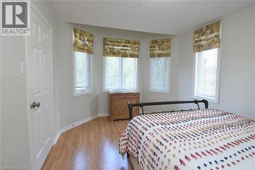 Bay window with three individual windows, wood-finish flooring, white paneled door, and neutral wall tones - 470 Amanda Crescent, Burlington, ON - Indoor Photo Showing Bedroom
