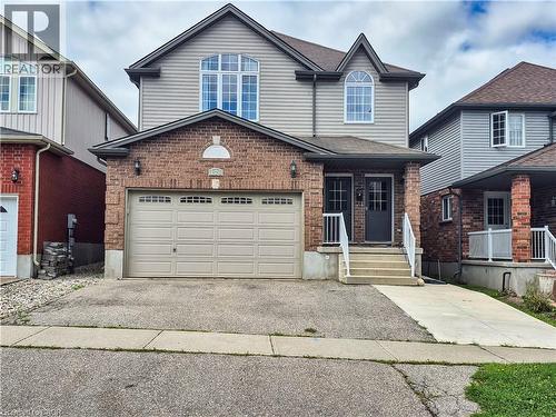 Two-story residence featuring brick and siding exterior, arched window accents, an integrated garage, and a covered entry with white railings - 128 Udvari Crescent Unit# A, Kitchener, ON - Outdoor With Facade