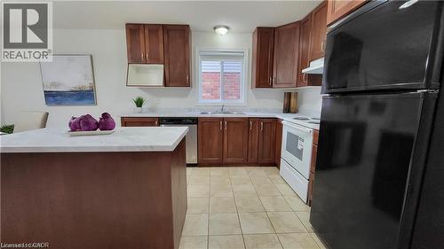 Kitchen featuring wood-finish cabinetry, tile flooring, white countertops, and a center island - 128 Udvari Crescent Unit# A, Kitchener, ON - Indoor Photo Showing Kitchen With Double Sink