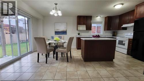 Kitchen featuring wood cabinetry, white appliances, and an island with a light-toned countertop - 128 Udvari Crescent Unit# A, Kitchener, ON - Indoor