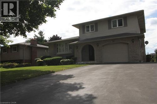 Multi-level residence featuring stone and siding exterior, arched entryway, attached garage, and mature landscaping - 14 Berkley Crescent, Simcoe, ON - Outdoor