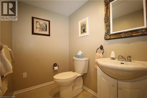 Pedestal sink with an integrated vanity cabinet, decorative wall mirror, and neutral wall paint - 14 Berkley Crescent, Simcoe, ON - Indoor Photo Showing Bathroom