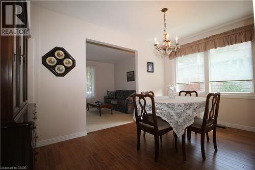 Wood-finish flooring, central chandelier, large window with blinds, and a wide doorway - 14 Berkley Crescent, Simcoe, ON - Indoor Photo Showing Dining Room