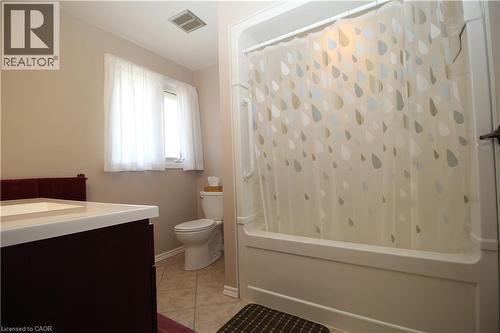 Bathroom featuring a vanity with an integrated sink, a toilet, a window, and a shower-over-bath combination - 14 Berkley Crescent, Simcoe, ON - Indoor Photo Showing Bathroom