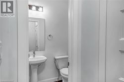White pedestal sink with a chrome faucet, illuminated by a three-light vanity fixture, and a rectangular wall-mounted mirror - 