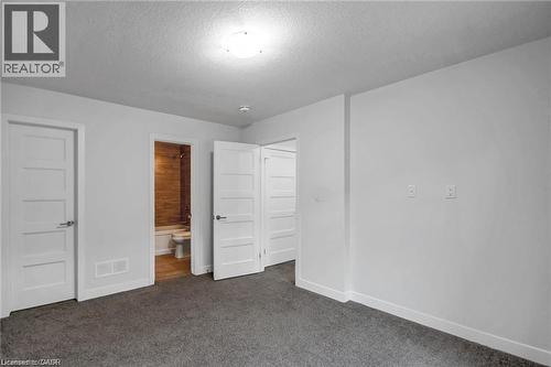 Plush carpet flooring, white interior doors, bright overhead lighting, and a modern bathroom with wood-look tile - 961 Battery Park, London, ON - Indoor Photo Showing Other Room