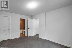 Plush carpet flooring, white interior doors, bright overhead lighting, and a modern bathroom with wood-look tile - 
