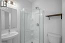 White pedestal sink with a chrome faucet, mirrored vanity, glass-enclosed shower, white toilet, and a wall-mounted wood-finish shelf - 961 Battery Park, London, ON  - Indoor Photo Showing Bathroom 