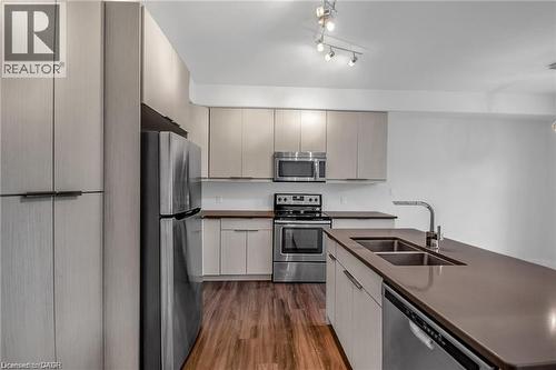 Modern kitchen featuring stainless steel appliances, wood-finish flooring, and a large island with an integrated double sink - 961 Battery Park, London, ON - Indoor Photo Showing Kitchen With Double Sink