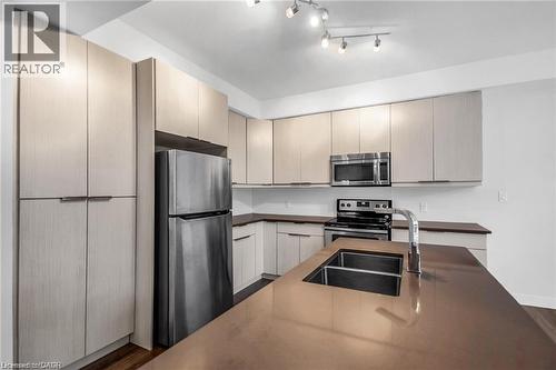 Contemporary kitchen featuring light wood-finish cabinetry, stainless steel appliances, a double basin sink, and an island with a polished countertop - 961 Battery Park, London, ON - Indoor Photo Showing Kitchen With Double Sink With Upgraded Kitchen
