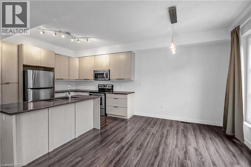 Kitchen featuring wood-finish flooring, stainless steel appliances, a center island with sink, track lighting, and a pendant light fixture - 961 Battery Park, London, ON - Indoor Photo Showing Kitchen With Double Sink