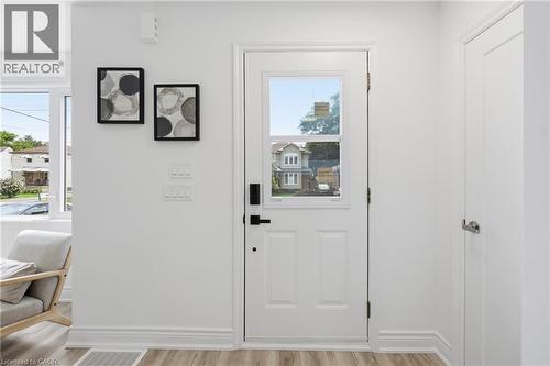 White paneled entry door with window, black door hardware, wood-finish flooring, and white trim - 156 East 36Th Street, Hamilton, ON - Indoor Photo Showing Other Room
