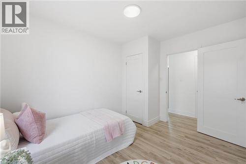 Recessed circular ceiling light, light wood-finish flooring, two white interior doors, and white painted walls - 156 East 36Th Street, Hamilton, ON - Indoor Photo Showing Bedroom