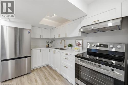 Kitchen featuring white cabinetry, light-colored countertops, stainless steel appliances, and wood-finish flooring - 156 East 36Th Street, Hamilton, ON - Indoor Photo Showing Kitchen