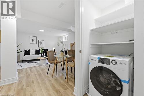 Integrated laundry appliance with built-in shelving, wood-finish flooring, recessed lighting, and white walls - 156 East 36Th Street, Hamilton, ON - Indoor Photo Showing Laundry Room
