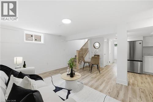 Expansive open-concept space featuring recessed lighting, wood-finish flooring, a contemporary staircase with wooden railings, and a built-in stainless steel refrigerator - 156 East 36Th Street, Hamilton, ON - Indoor Photo Showing Living Room