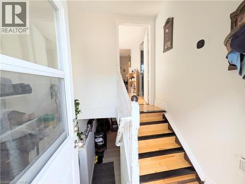 Hardwood stair treads with a painted riser accent, painted newel post and balusters, and a solid entry door with a screen - 7 Campbell Avenue, Hamilton, ON - Indoor Photo Showing Other Room