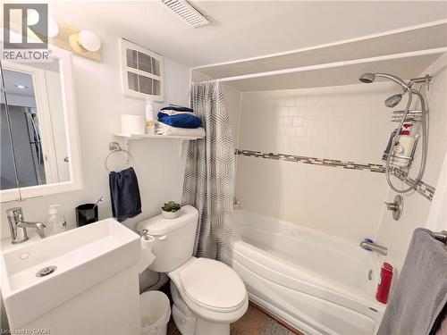 Full bath featuring a white vanity with an integrated rectangular sink, wall-mounted mirror, and a combination shower and tub with subway tile surround and decorative accent band - 7 Campbell Avenue, Hamilton, ON - Indoor Photo Showing Bathroom