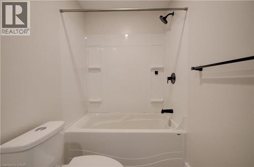 Tub and shower combination featuring a white surround, matte black fixtures, and integrated shelving - 361 Prospect Avenue, Kitchener, ON - Indoor Photo Showing Bathroom