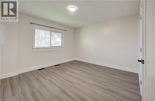 Bright room featuring wood-finish flooring, a white window frame with a black curtain rod, and a flush-mount ceiling light - 361 Prospect Avenue, Kitchener, ON - Indoor Photo Showing Other Room