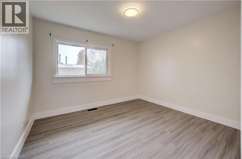 Neutral-toned room featuring wood-finish flooring, a white trim window, and a flush-mount ceiling light - 361 Prospect Avenue, Kitchener, ON - Indoor Photo Showing Other Room