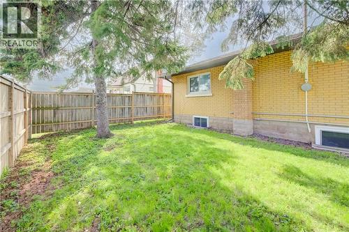 Fenced backyard featuring a mature tree, a manicured lawn, and a light-colored brick exterior - 361 Prospect Avenue, Kitchener, ON - Outdoor