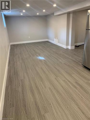 Spacious room featuring wood-finish flooring, recessed ceiling lighting, a window, and neutral wall paint - 361 Prospect Avenue, Kitchener, ON - Indoor