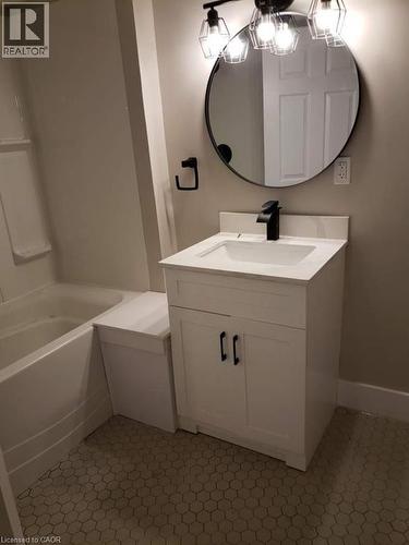 Bathroom featuring a white vanity with a rectangular sink, a black single-handle faucet, and a circular black-framed mirror - 361 Prospect Avenue, Kitchener, ON - Indoor Photo Showing Bathroom