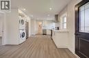 Open-concept kitchen featuring wood-finish flooring, white cabinetry with contemporary hardware, light-toned countertops, and a white subway tile backsplash - 361 Prospect Avenue, Kitchener, ON  - Indoor Photo Showing Laundry Room 