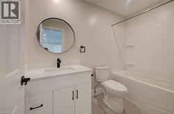 Bathroom featuring a white vanity with integrated sink, a dark finish single-handle faucet, and a round wall-mounted mirror - 