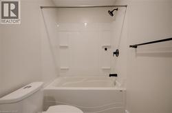 Tub and shower combination featuring a white surround, matte black fixtures, and integrated shelving - 