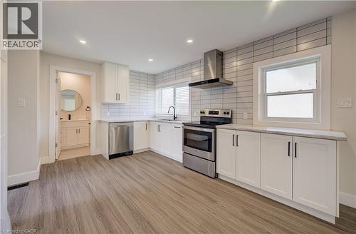 Contemporary kitchen featuring white shaker cabinetry, stainless steel appliances, light wood-finish flooring, and subway tile backsplash - 361 Prospect Avenue, Kitchener, ON - Indoor Photo Showing Kitchen