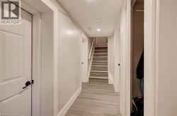 Hallway featuring wood-finish flooring, recessed lighting, and a stairway with carpeted treads - 