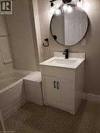 Bathroom featuring a white vanity with a rectangular sink, a black single-handle faucet, and a circular black-framed mirror - 