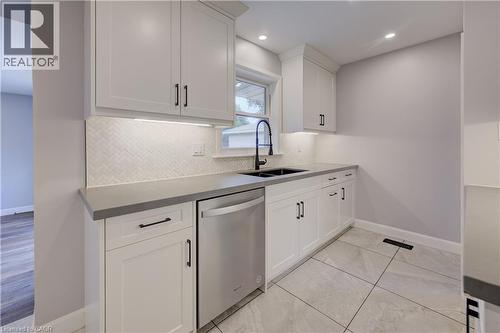 White shaker cabinetry, herringbone tile backsplash, under-cabinet lighting, dark countertop, and large format tile flooring - 244 Royal Street, Waterloo, ON - Indoor Photo Showing Kitchen With Double Sink