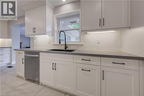 White shaker-style cabinetry with matte black hardware, under-cabinet lighting, herringbone tile backsplash, integrated stainless steel dishwasher, and a black sink with a gooseneck faucet - 244 Royal Street, Waterloo, ON - Indoor Photo Showing Kitchen