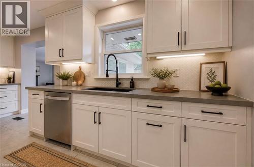 White shaker cabinetry, dark countertops, white herringbone tile backsplash, stainless steel dishwasher, and a black gooseneck faucet - 244 Royal Street, Waterloo, ON - Indoor Photo Showing Kitchen With Upgraded Kitchen
