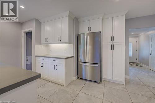 White shaker cabinetry, stainless steel French door refrigerator, light gray countertops, white geometric tile backsplash, and light gray tile flooring - 244 Royal Street, Waterloo, ON - Indoor Photo Showing Kitchen
